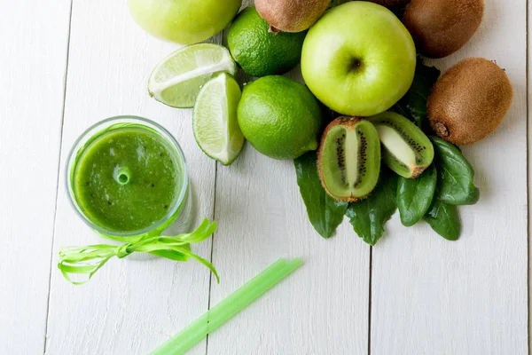 Batido verde cerca de los ingredientes para ello sobre fondo de madera blanca. Manzana, lima, espinacas. Desintoxicación. Bebida saludable. Vista superior . —  Fotos de Stock