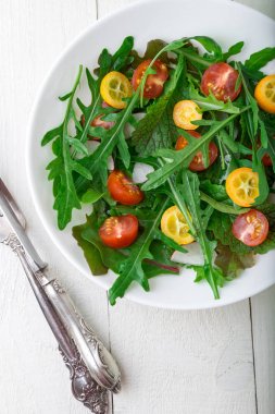 Beyaz ahşap zemin üzerinde Kamkat ve domates kiraz ile taze Roka Salatası. Üstten Görünüm. Sağlıklı gıda. Diyet.