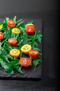 Vejetaryen Roka Salatası ile kayrak plaka üzerinde Kamkat ve domates kiraz. Sağlıklı gıda. Diyet