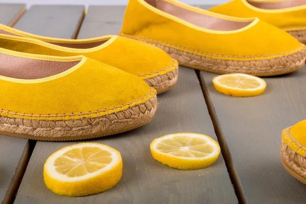 Sepatu espadrilles kuning dekat irisan lemon di latar belakang kayu. Tutup. . — Stok Foto