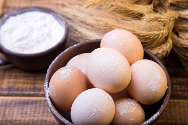 Ekmek için malzemeler. Taze yumurta bir kahverengi kase, buğday ve un ahşap arka plan üzerinde. Yakın çekim.
