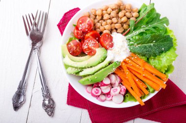 Vegan Buda kase Beyaz ahşap zemin üzerinde. Havuç, marul, kiraz domates, turp, avokado ve Nohut ile top. Vejetaryen, sağlıklı, detoks gıda kavramı. Üstten Görünüm.