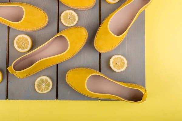 Zapatos de alpargatas amarillas cerca de rodajas de limón sobre fondo de madera. Vista superior. — Foto de Stock