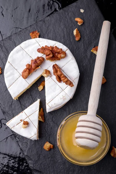 Peynir camembert ceviz ve siyah arduvaz levha zemin üzerine honyey o. Üstten Görünüm.