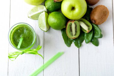 Yeşil smoothie yakınındaki beyaz ahşap zemin üzerinde bunun için malzemeler. Elma, limon, ıspanak. Detoks. Sağlıklı içecek. Üstten Görünüm.
