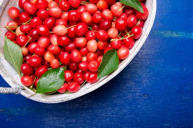 Mavi ahşap arka plan üzerinde beyaz sepet içinde kırmızı kiraz. Kiraz kapatın. Üstten Görünüm. Kopya alanı.