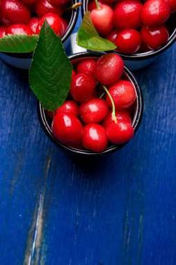 Kiraz emaye Kupası mavi ahşap zemin üzerinde. Sağlıklı, yaz meyve. Kiraz. Üstten Görünüm. Kopya alanı.