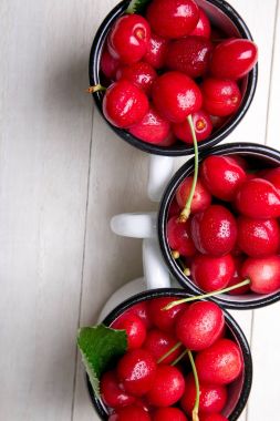 Kiraz emaye Kupası Beyaz ahşap zemin üzerinde. Sağlıklı, yaz meyve. Kiraz. Üstten Görünüm.