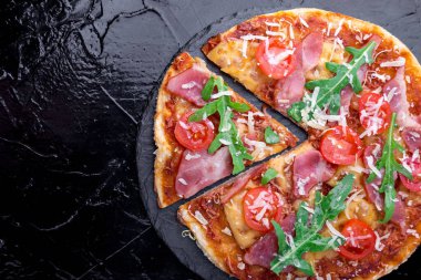 Ev yapımı pizza salam, domates, roka siyah arduvaz gemide. Üstten Görünüm. Kopya alanı.