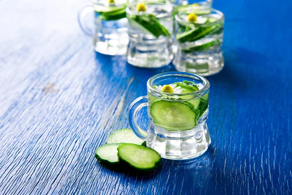 Cucumber water in little mason glass jar on blue background. Rustic. Detox.