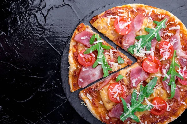 Ev yapımı pizza salam, domates, roka siyah arduvaz gemide. Üstten Görünüm. Kopya alanı.