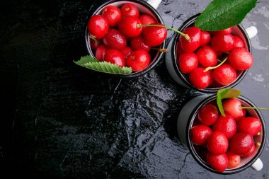 Kiraz emaye Kupası siyah arka plan üzerine. Sağlıklı, yaz meyve. Kiraz. Üstten Görünüm.