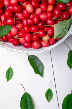 Beyaz ahşap zemin üzerinde beyaz sepet içinde kırmızı kiraz. Kiraz yakın çekim.
