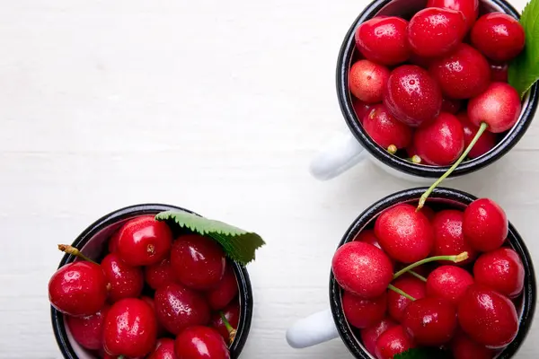 Ciliegia in tazza di smalto su sfondo bianco in legno. Frutta sana ed estiva. Ciliegie. Vista dall'alto . — Foto Stock