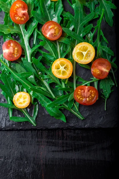 Vejetaryen Roka Salatası ile kayrak plaka üzerinde Kamkat ve domates kiraz. Üstten Görünüm. Sağlıklı gıda. Diyet.