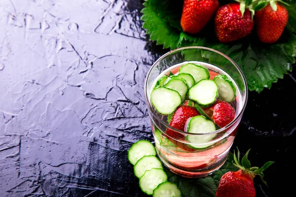 Komkommer en aardbei detox water in glas op zwarte achtergrond. Achtergrondverlichting. Dieet. — Stockfoto