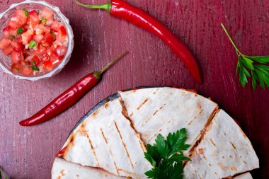Mexican quesadilla kırmızı ahşap arka plan üzerinde siyah arduvaz taş plaka üzerinde salsa ile. Biber biber. Üstten Görünüm.