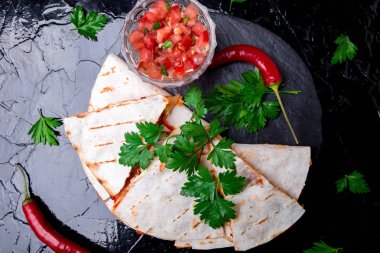 Mexican quesadilla siyah arduvaz taş plaka üzerinde salsa sos ile. Biber biber. Üstten Görünüm.