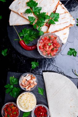 Mexican quesadilla ve siyah arduvaz taş plaka üzerinde salsa malzemelerle. Üstten Görünüm.