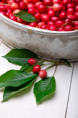 Beyaz ahşap zemin üzerinde beyaz sepet içinde kırmızı kiraz. Kiraz yakın çekim.