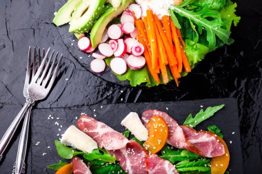 İki farklı salata om siyah taşı kayrak. Vegan salata. Et salatası. Jambon jamon serrano, camembert, kavun, roka salatası. Üstten Görünüm.