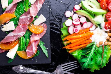 İki farklı salata om siyah taşı kayrak. Vegan salata. Et salatası. Jambon jamon serrano, camembert, kavun, roka salatası. Üstten Görünüm.