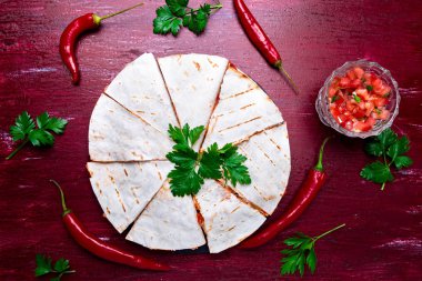 Mexican quesadilla kırmızı ahşap arka plan üzerinde siyah arduvaz taş plaka üzerinde salsa ile. Biber biber. Üstten Görünüm.