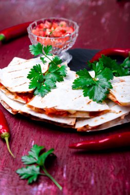Mexican quesadilla kırmızı ahşap arka plan üzerinde siyah arduvaz taş plaka üzerinde salsa ile. Biber biber.