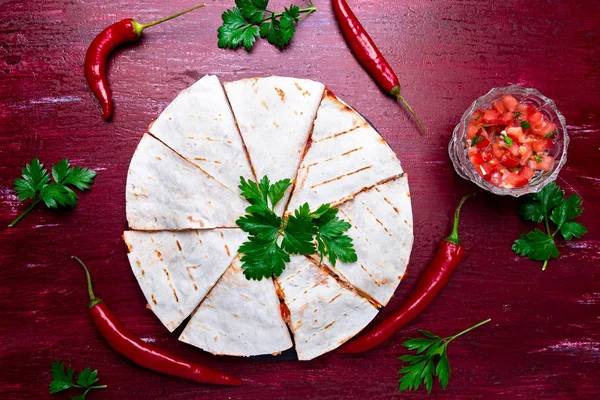 Mexican quesadilla kırmızı ahşap arka plan üzerinde siyah arduvaz taş plaka üzerinde salsa ile. Biber biber. Üstten Görünüm.