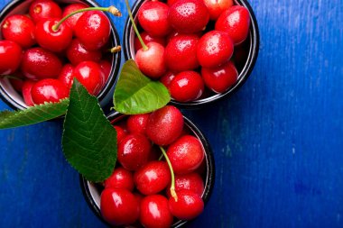 Kiraz emaye Kupası mavi ahşap zemin üzerinde. Sağlıklı, yaz meyve. Kiraz