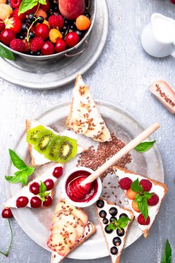 Gri arka plan üzerinde meyve tost. Sağlıklı kahvaltı. Temiz yemek. Diyet kavramı. Tahıl ekmek dilimleri ile krem peynir ve çeşitli meyve, meyveler, tohumlar. Vejetaryen. Üstten Görünüm.