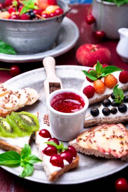 Kırmızı zemin üzerine meyve tost. Sağlıklı kahvaltı. Temiz yemek. Diyet kavramı. Tahıl ekmek dilimleri ile krem peynir ve çeşitli meyve, meyveler, tohumlar. Vejetaryen.