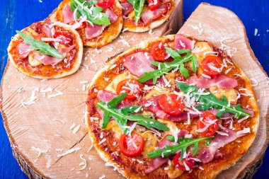 Ev yapımı pizza salam, domates, roka ahşap Pano mavi zemin üzerine. Üstten Görünüm.