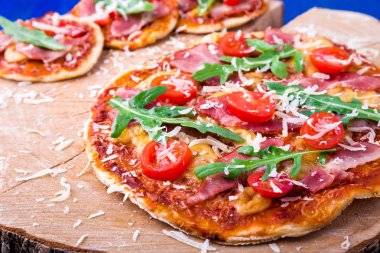 Ev yapımı pizza salam, domates, roka ahşap Pano mavi zemin üzerine