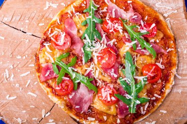 Ev yapımı pizza salam, domates, roka ahşap Pano mavi zemin üzerine. Üstten Görünüm.