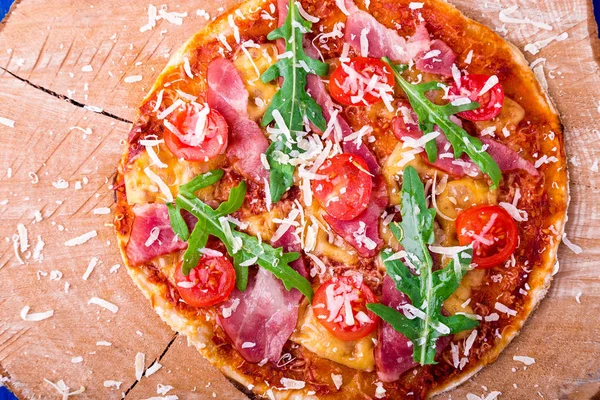 Ev yapımı pizza salam, domates, roka ahşap Pano mavi zemin üzerine. Üstten Görünüm.