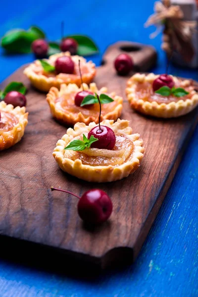 Tarte mici de caramel de mere pe placă de lemn și fundal rustic albastru. Tatuaj francez cu mere paradis. Close up . — Fotografie, imagine de stoc