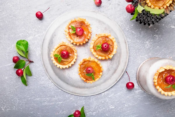 Elma gri arka plan üzerine karamel küçük tarts. Cennet elması ile Fransız tatin. Üstten Görünüm.
