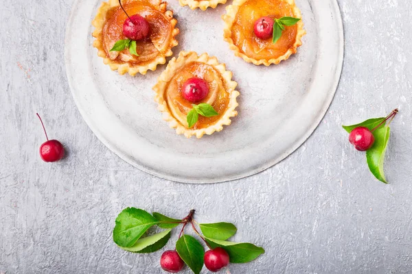Elma gri arka plan üzerine karamel küçük tarts. Cennet elması ile Fransız tatin. Üstten Görünüm.