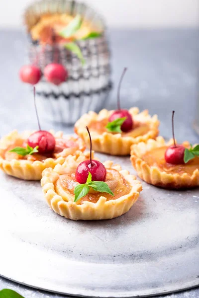 Elma gri arka plan üzerine karamel küçük tarts. Cennet elması ile Fransız tatin.
