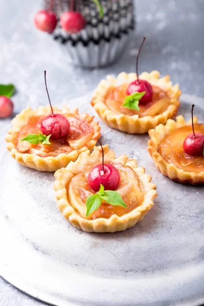 Elma gri arka plan üzerine karamel küçük tarts. Cennet elması ile Fransız tatin.