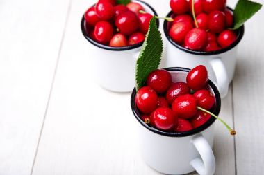 Kiraz emaye Kupası Beyaz ahşap zemin üzerinde. Sağlıklı, yaz meyve. Kiraz