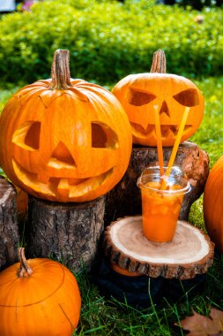 Arka planda balkabağı desenli Cadılar Bayramı kokteyli. Parti için yumruk. İki Jack-o-Lantern kokteyl içiyor..