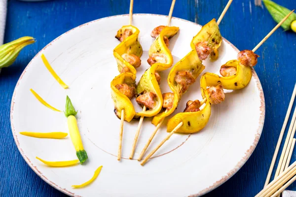 Abobrinha e frango kebab em pau de madeira na placa branca e fundo azul. Fechar — Fotografia de Stock