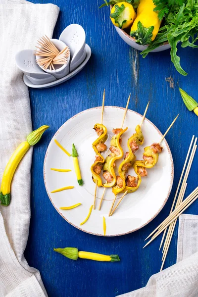 Kabak ve tavuk kebap beyaz plaka ve mavi arka plan üzerinde tahta sopa üzerinde. Üstten Görünüm.