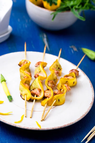 Abobrinha e frango kebab em pau de madeira na placa branca e fundo azul. Fechar — Fotografia de Stock