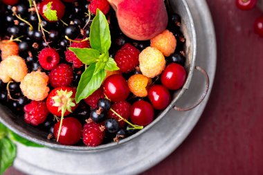 Meyve ve çilek kırmızı zemin üzerine gri metal kabın içinde karıştırın. Üstten Görünüm. Temiz yemek.