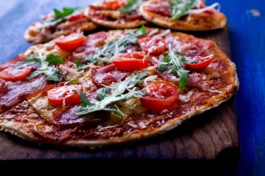 Ev yapımı pizza salam, domates, roka ahşap Pano mavi zemin üzerine.