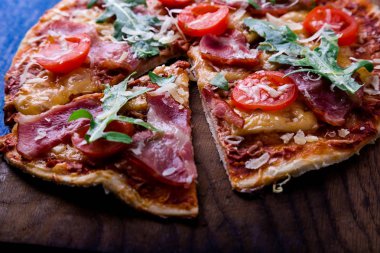 Ev yapımı pizza salam, domates, roka ahşap Pano mavi zemin üzerine.