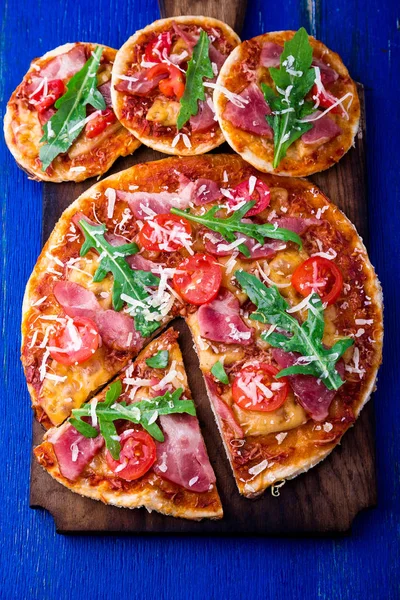 Ev yapımı pizza salam, domates, roka ahşap Pano mavi zemin üzerine. Üstten Görünüm.